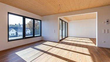 Innenansicht eines Wohnraumes, lichtdurchflutet mit großen Fenstern